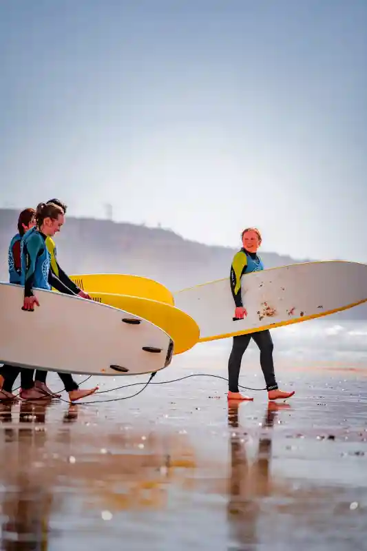 Um grupo de aula de surf a caminhar na praia com as pranchas perto de Lagos