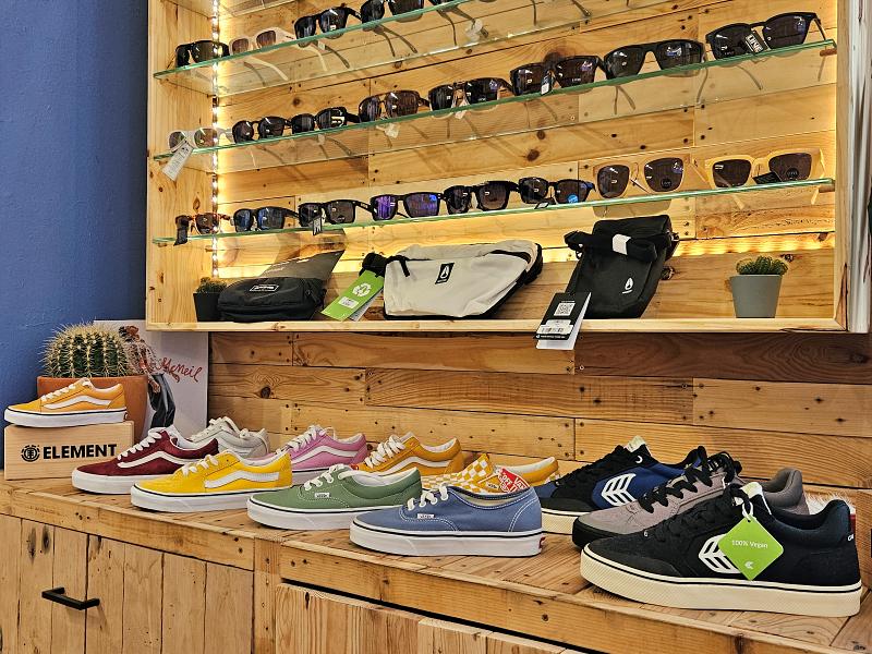 display of various types of shoes and sunglasses on a wooden shelf