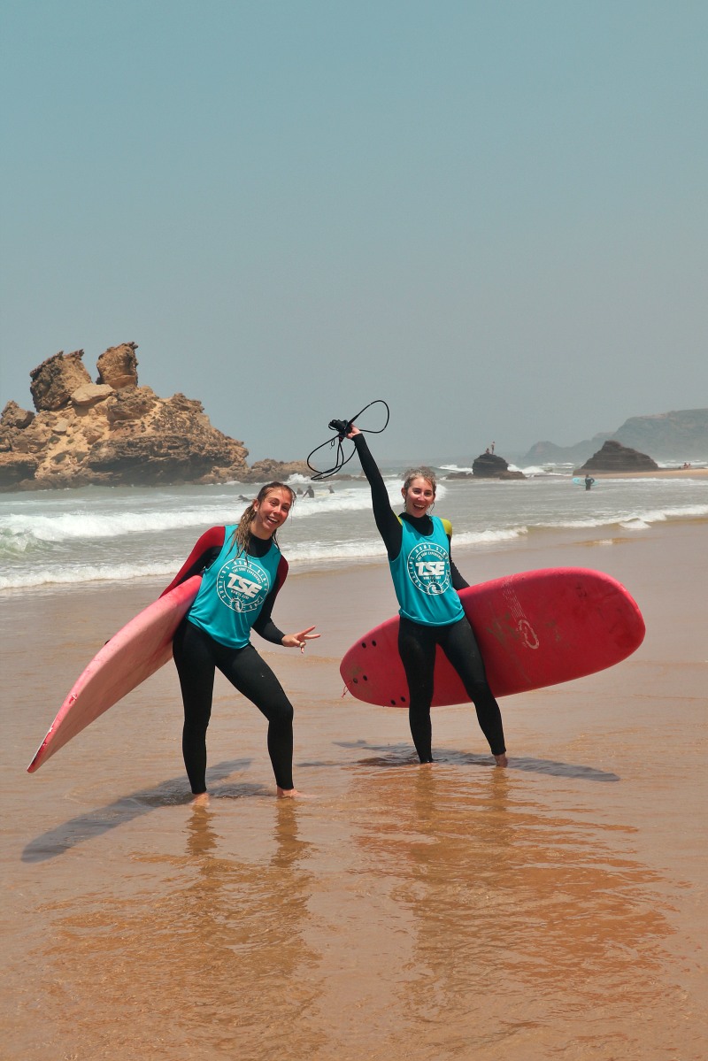 people learning surfing and carrying their surfboard