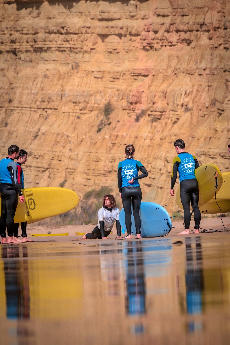 people learning surfing and carrying their surfboard